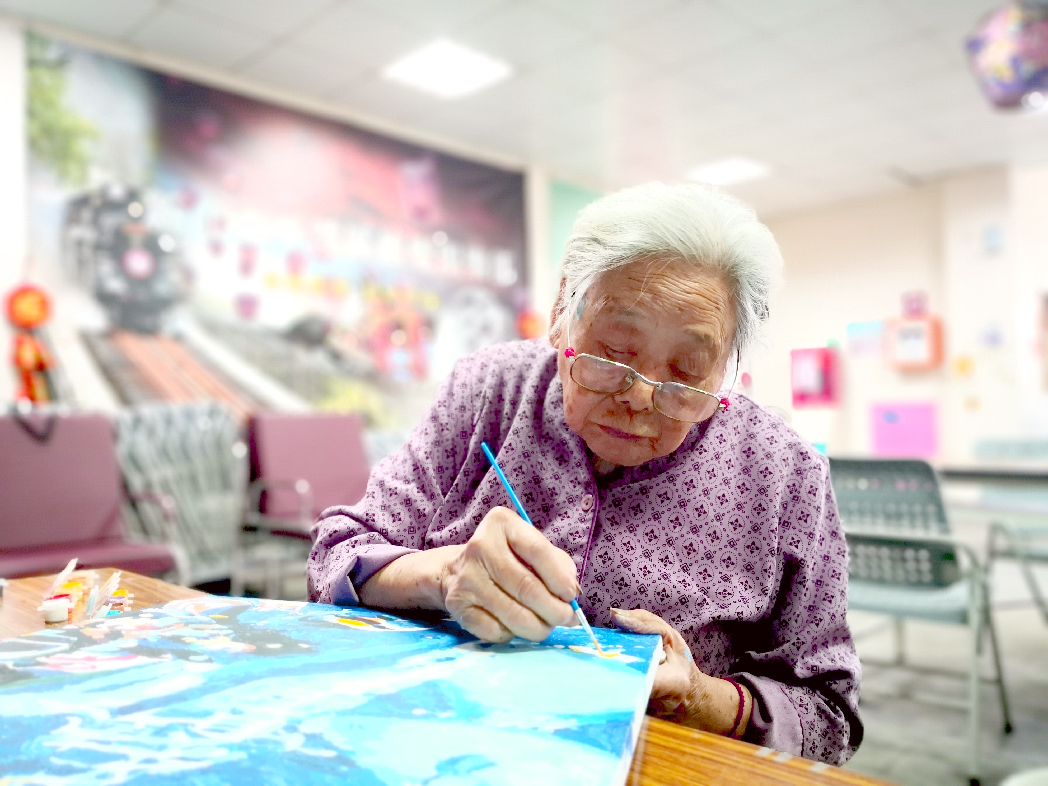  高齡95歲的長輩專心地描繪畫作。（攝影／一粒麥子基金會提供）